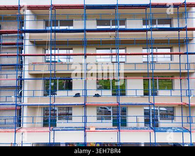 Die Arbeiter sind auf einer Baustelle beschäftigt, auf der Gerüste um ein Gebäude herum aufgestellt werden. Die Szene zeigt, wie die neue Struktur ihren letzten Schliff erhält Stockfoto