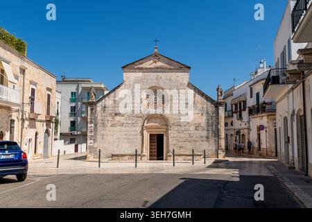 Locorotondo - Apulien - Italien - 25.06.2025: Fassade der Chiesa Rettoria Madonna della Greca in Locorotondo mit Rosenfenster, Statuen und umgebenden Wohn- und Stadtgebäuden. Stockfoto