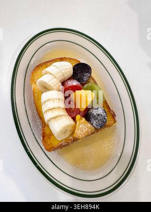 Nahaufnahme von süßem französischem Toast mit frischen Früchten wie Banane, Kiwi, Trauben und Orangenscheiben. Helles Frühstück und gesundes Brunch-Konzept. Stockfoto