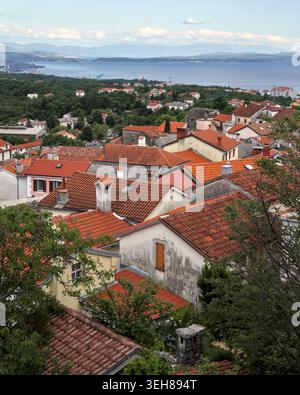 Vertikale Aufnahme von alten mediterranen Häusern und roten Ziegeldächern in Kastav, Kroatien, mit Blick auf das Meer und die Küste. Stockfoto
