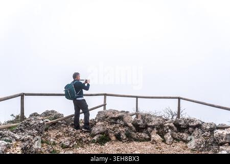 Wanderer fotografieren den nebligen Blick auf die Berge und genießen die Natur Stockfoto