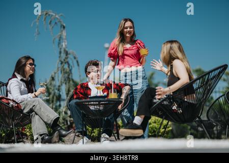 Freunde im Teenageralter treffen sich auf einer sonnigen Terrasse mit Getränken und lässiger Sommerkleidung Stockfoto