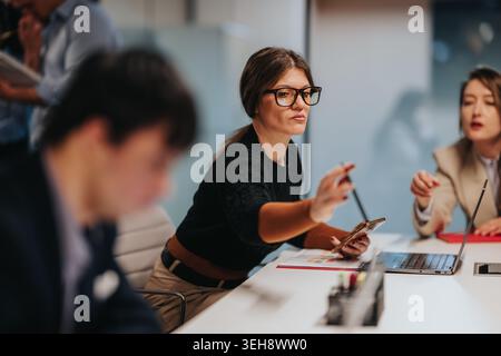 Geschäftsfrau, die ein gemeinsames Meeting in einem modernen Büro mit Laptop und Smartphone leitet Stockfoto