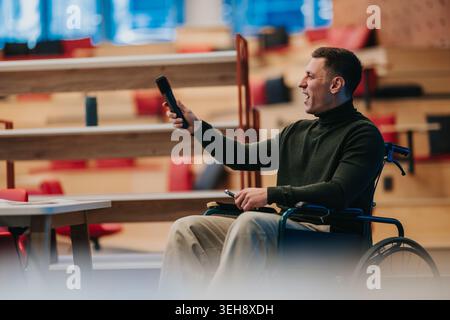 Geschäftsmann im Rollstuhl, der eine Präsentation mit Fernbedienung in einem modernen Büroauditorium hält Stockfoto
