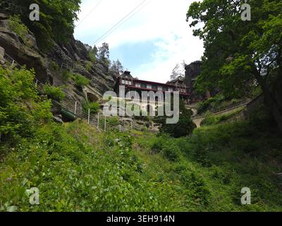 Das majestätische Pravcice Tor, der größte natürliche Sandsteinbogen Europas, die Böhmische Schweiz. Historisches Haus in felsigen Klippen, umgeben von lu Stockfoto