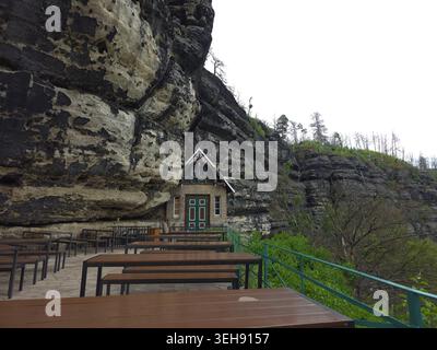 Das majestätische Pravcice Tor, der größte natürliche Sandsteinbogen Europas, die Böhmische Schweiz. Ein Steinhaus, das in eine Klippe gebaut wurde, mit Holz im Freien Stockfoto
