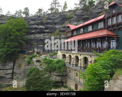 Das majestätische Pravcice Tor, der größte natürliche Sandsteinbogen Europas, die Böhmische Schweiz. Hotel an der Klippe mit Holzveranda auf Kalkstein Stockfoto