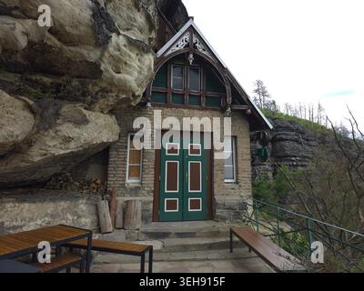 Das majestätische Pravcice Tor, der größte natürliche Sandsteinbogen Europas, die Böhmische Schweiz. Steinhaus in Klippe gebaut mit grüner Tür, Holz Stockfoto