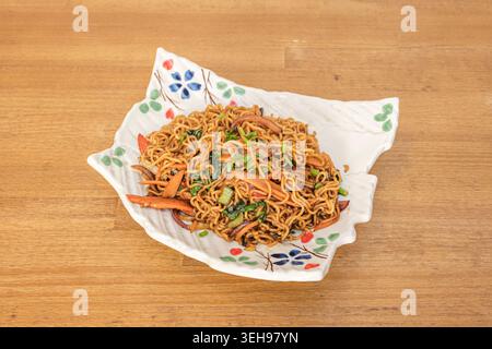 Bei einem Schuss aus einem niedrigen Winkel werden breite Reisnudeln (HO Fun) mit Austernsauce, Rindfleisch, grüner Paprika, Zwiebeln und Sojasprossen gebraten. serviert in einer Tiefe Stockfoto