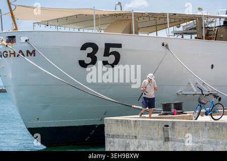 Key West, FL, USA - 21. Mai 2026: Ein alter Mann fischt mit einem Küstenwachschiff in Key West Florida Stockfoto