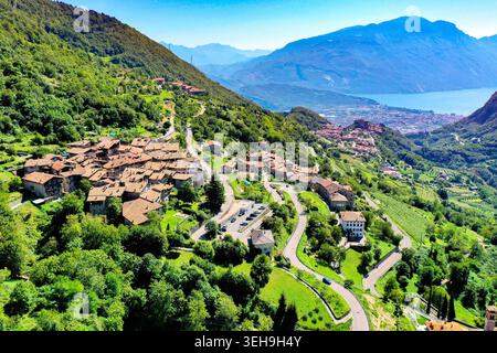 Blick aus der Vogelperspektive auf das historische Steindorf Canale di Tenno, eingebettet zwischen üppig grünen Bergen mit dem Gardasee im Hintergrund Ville del Monte, Tre Stockfoto