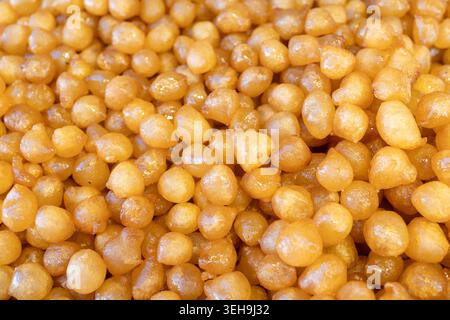 Ein dichter Vollbild aus der Nähe zeigt einen großen Haufen frisch gebratener Awameh oder Luqaimat, die traditionelle süße Teigbällchen aus dem Nahen Osten sind. Die Stockfoto