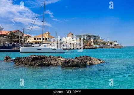 Ein Katamaran-Segelboot, das im klaren türkisfarbenen Karibischen Meer entlang der felsigen tropischen Uferpromenade von George Town in den Cayman Islands Vacation des vor Anker geht Stockfoto
