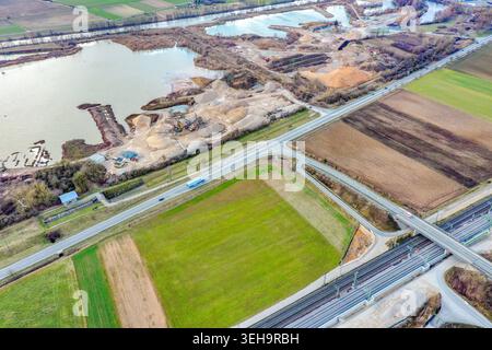 Luftaufnahme eines Kiesbruchs mit Sandpfählen und schweren Maschinen neben einem Fluss und Bahngleisen in einer ländlichen Landschaft Buttenheim, Bayern, Deutsch Stockfoto