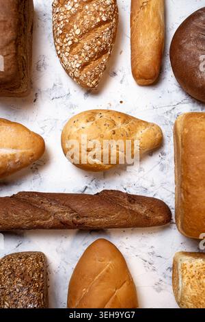 Verschiedene Arten von frischem Brot und Backwaren in einer flachen Komposition auf einem hellen strukturierten Hintergrund angeordnet. Stockfoto