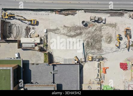 Aus der Vogelperspektive auf eine geschäftige Baustelle mit gelben Baggern, schweren Maschinen und Erdhaufen in der Nähe der städtischen Gebäude Sariyer, Istanbul, Turkiye. Stockfoto