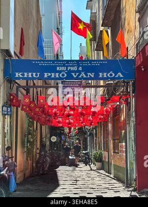 Zwei Touristen spazieren durch eine enge, mit roten Laternen geschmückte Kulturgasse in Ho Chi Minh City, Vietnam – 22. März 2026. Stockfoto