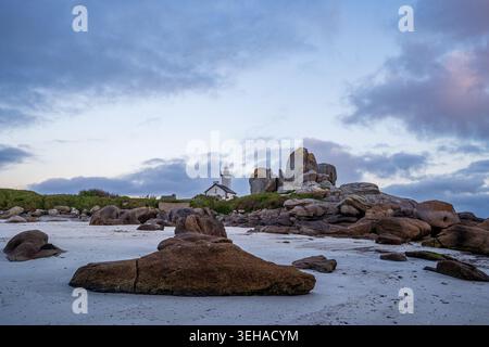 Der Leuchtturm Pontusval steht einsam hinter riesigen Granitformationen am weißen Strand von Brignogan. Ein Niedrigwinkelbild, das die Leistungsfähigkeit der Finis unterstreicht Stockfoto