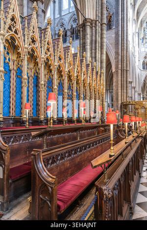 Im Inneren der Westminster Abbey befindet sich der Chor mit hölzernen Chorbuden, die ordentlich angeordnet sind. Jeder Stand ist mit roten Lampen und blauen Details ausgestattet. Stockfoto