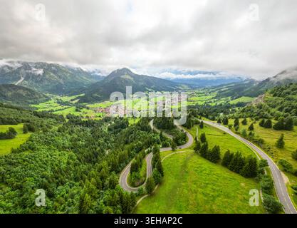 Ein atemberaubender Blick aus der Luft fängt die gewundenen, asphaltierten Straßen der alpinen Serpentinen ein, eingebettet in üppige grüne Landschaften und majestätische Berge, i Stockfoto