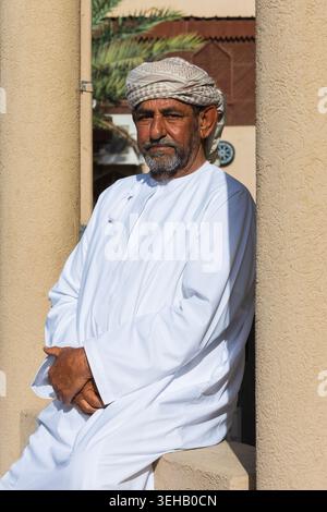 Ein Mann in omanischer Kleidung mit Turban (massar), einem langen weißen Gewand (Dschingdasha) mit Quaste (Furakha) am Nizwa Central Souq in Nizwa, Oman Stockfoto