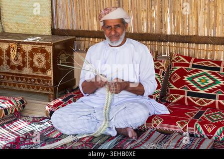 Ein omanischer Korbweber (Handwerker) bei der Arbeit im Nizwa Fort aus dem 17. Jahrhundert in Nizwa, Oman Stockfoto