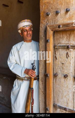 Ein omanischer Mann in traditioneller omanischer Kleidung mit Turban (massar), einem langen weißen Gewand (Dschingdasha) mit Quaste (Furakha) im Nizwa Fort in Nizwa, Oman Stockfoto