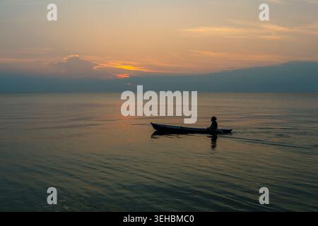 Silhouette eines Garifuna-Fischers, der sein Boot in der Karibik in Livingston, Guatemala paddelt. Stockfoto