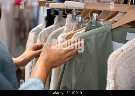 Nahaufnahme einer Frau, die durch neue Kleidungsstücke stöbert Stockfoto