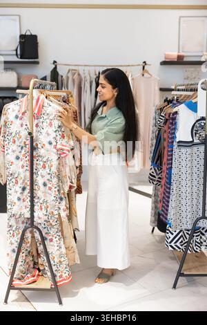 Junge Indianerin, die Blumenkleider im Bekleidungsgeschäft durchsucht Stockfoto