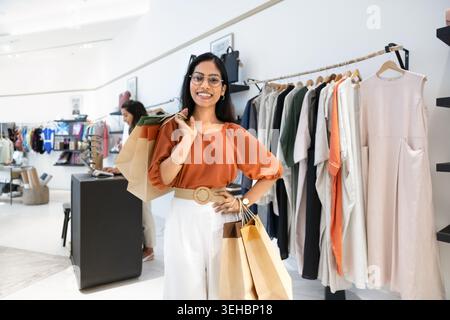 Frau, die in einem Damenladen mit Einkaufstaschen steht Stockfoto