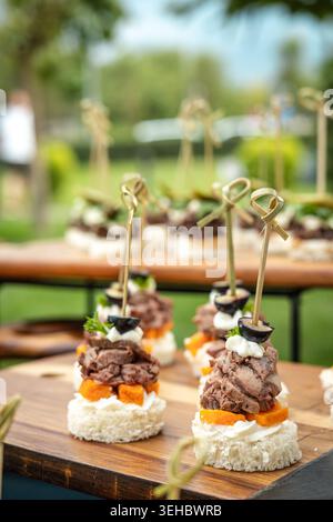 Elegante kleine Vorspeisen mit Fleisch und Oliven auf Holztabletts für ein Bankett. Stockfoto