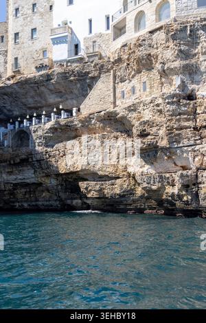 Polignano a Mare, Italien, Apulien - 24. Mai 2024: Gebäude auf Klippen gebaut, Blick vom Meer auf die Felsen und Höhlen von ​​picturesque.Terrasse mit weltberühmter Ruhe Stockfoto
