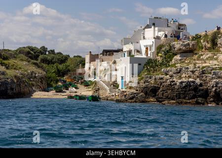 Polignano A Mare, Italien, Apulien - 24. Mai 2024: Malerische Bucht Cala Sala, natürlicher felsiger Strand mit traditionellen Fischerbooten und blauem Wasser Stockfoto