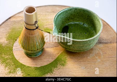 Nahaufnahme der Bambus-chasen-Schneebesen, die in einer Matcha-Keramikschale mit grünem Pulverrückstand ruhen. Haptische Textur und Handwerkskunst auf rustikaler Wook Stockfoto
