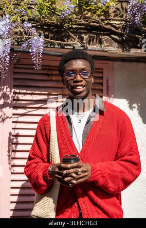 Modischer positiver afroamerikanischer Mann Student posiert draußen in der Stadt und lächelt vor der Kamera Stockfoto