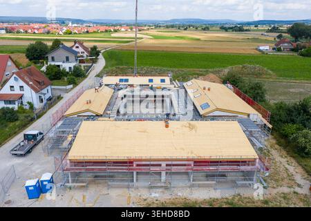 Igensdorf, Deutschland - 11. Mai 2024: Luftaufnahme einer großen Baustelle mit Arbeitern und Gerüsten, umgeben von Feldern und Häusern. Stockfoto