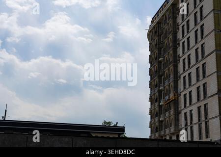 Modernes mehrstöckiges Wohngebäude unter bewölktem Himmel mit urbaner Atmosphäre und Kopierraum. Zeitgenössische Stadtarchitektur im Hintergrund Stockfoto