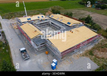 Igensdorf, Deutschland - 11. Mai 2024: Aus der Vogelperspektive eines im Bau befindlichen Wohngebäudes mit Holzdächern und Gerüsten, umgeben von Grün Stockfoto