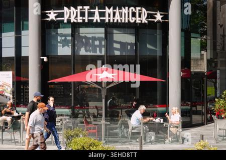 Leute sitzen vor dem Café Pret A Manger mit einem großen roten Regenschirm im Spinningfields-Viertel von Manchester, England, Großbritannien Stockfoto