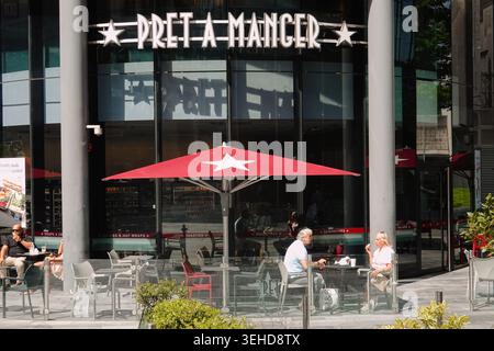 Leute sitzen vor dem Café Pret A Manger mit einem großen roten Regenschirm im Spinningfields-Viertel von Manchester, England, Großbritannien Stockfoto