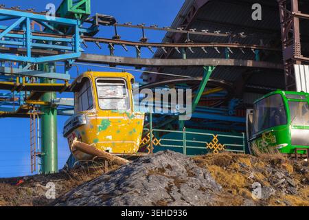 Alte und verlassene gelbe Gondelbahn an einer rustikalen Bergstation mit mechanischer Seilrolleninfrastruktur Stockfoto
