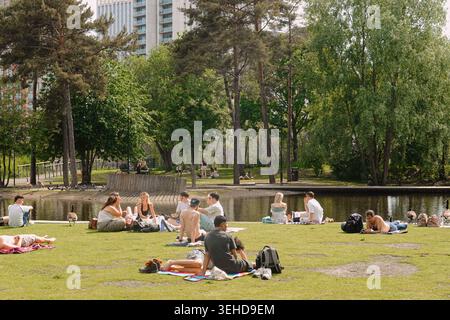 Menschen, die sich auf dem Rasen im Cotton Field Park in New Islington, Manchester, England, Großbritannien, entspannen Stockfoto