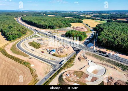 Nürnberg, Deutschland - 18. Mai 2024: Luftaufnahme der A73 mit Kränen, schweren Maschinen und Lkw, die durch einen Wald fahren Stockfoto