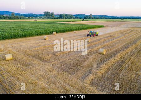 Nürnberg, Deutschland - 02. Mai 2026: Luftaufnahme des Landwirtschaftsgebiets Knoblauchsland mit Traktorballenheu und Rundballen über goldflossen verstreut Stockfoto