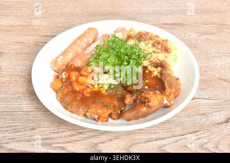 Gegrilltes Schweinefleisch-Steak-Dressing mit süß-saurer Soße, Spaghetti und Kohl-Salat, paar Würstchen auf Teller Stockfoto