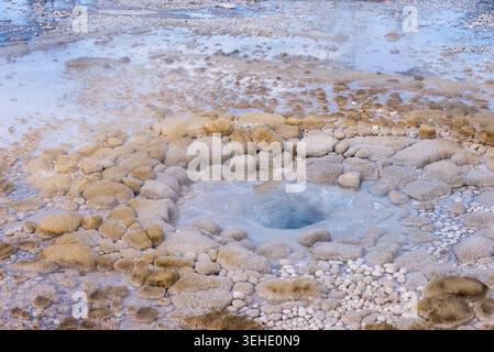 Blick aus der Nähe auf einen lebendigen geothermischen Thermalpool, umgeben von Mineralablagerungen und Dampf Stockfoto