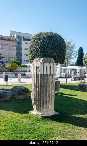 Die historischen Ruinen des Forum Romanum in Zadar, mit einem archäologischen Museum und Fußgängern, die auf einem sonnigen platz spazieren. Stockfoto