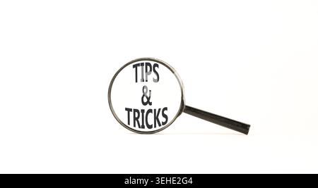 Symbol für Tipps und Tricks. Konzeptworte Tipps und Tricks auf einer wunderschönen Lupe. Schöner weißer Hintergrund. Geschäftliche Tipps und Tricks motiva Stockfoto