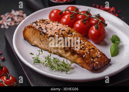 Essen, köstlicher frischer gegrillter roter Fisch mit Salz, Gewürzen und Kräutern auf dunklem Betonhintergrund Stockfoto